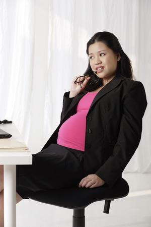 Profile of pregnant businesswoman at deskの写真素材