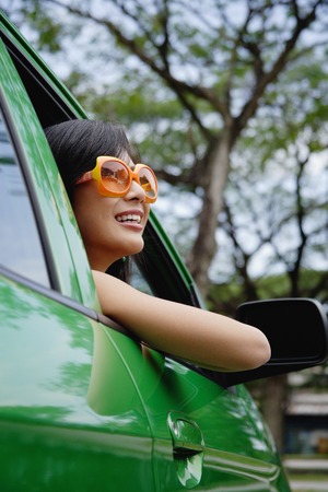 A young woman drives a green carの写真素材