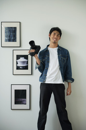 Young man with camera, smiling at camera