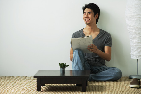 Young man sitting on floor while writingの写真素材