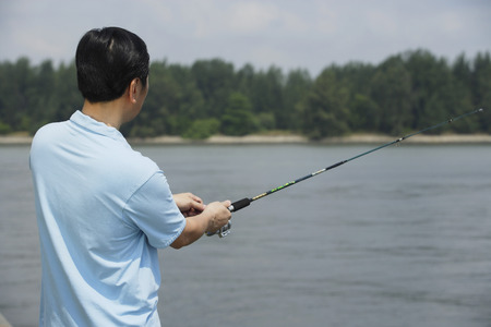 Man fishing with fishing pole, rear viewの写真素材