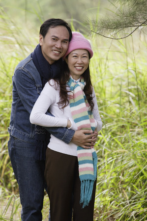Man and woman wearing hat and scarves, standing outdoors in natureの写真素材