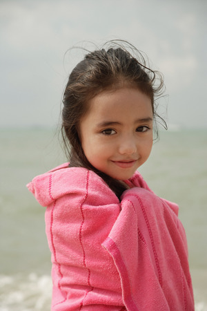 Young girl on beach wrapped in pink towelの写真素材