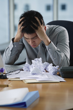 A man looks stressed as he works at his deskの写真素材