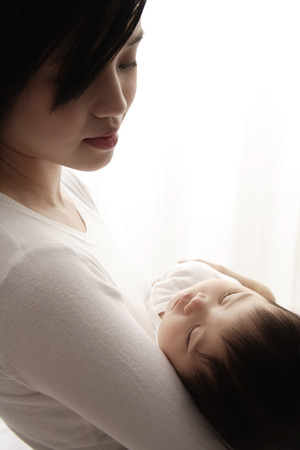Woman holding sleeping babyの写真素材