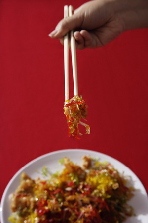 Woman tossing raw fish salad also known as 'Yu Sheng' or 'Lo Hei'の写真素材