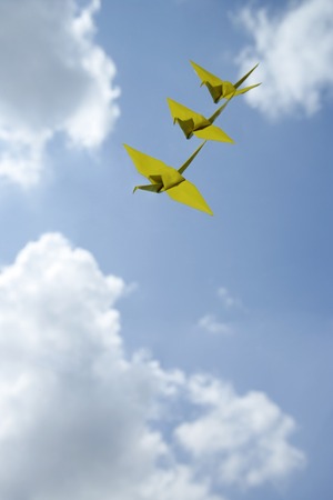 3 yellow paper cranes against sky backdrop
