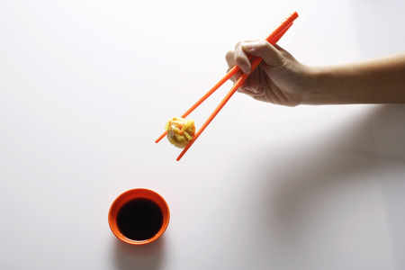 hand holding dimsum between orange chopsticksの写真素材