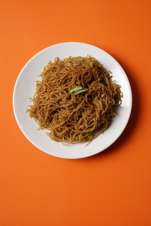Noodles on plate on orange place mat.の写真素材