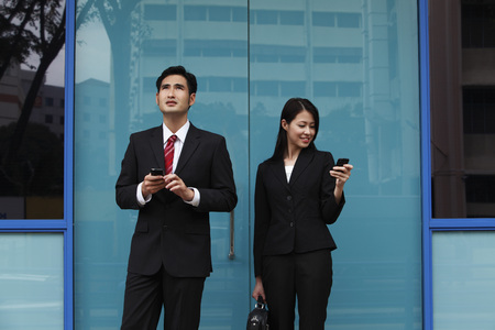 man and woman wearing suites and holding phonesの写真素材
