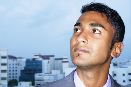 Businessman looking away, buildings in the backgroundの写真素材