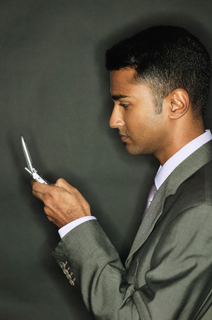 Businessman using mobile phone, side viewの写真素材