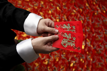 Cropped shot of man holding lucky Hong Bao, red envelopeの写真素材