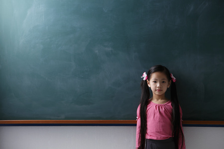 Young girl with pony tails standing in front of chalkboardの写真素材