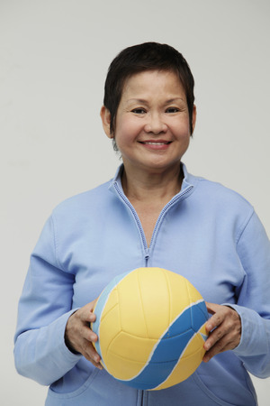 Mature Chinese woman holding a volleyballの写真素材