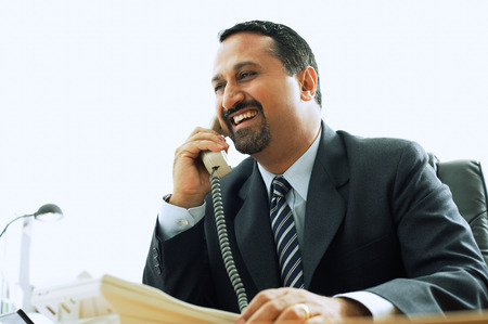 Businessman using telephone in office, smiling
