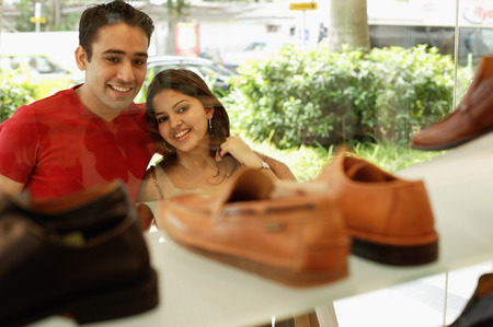 Young man and woman standing outside shoe shop looking at window displayの写真素材