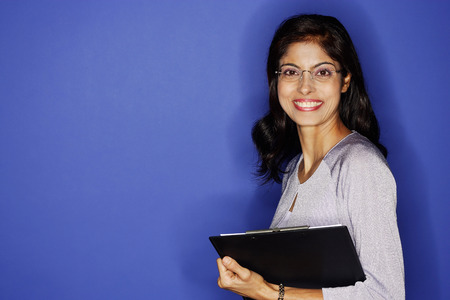 Woman looking at camera, carrying clipboardの写真素材