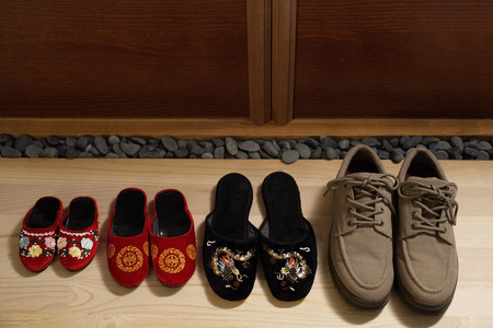 top view of slippers and shoes placed in a row at door frontの写真素材