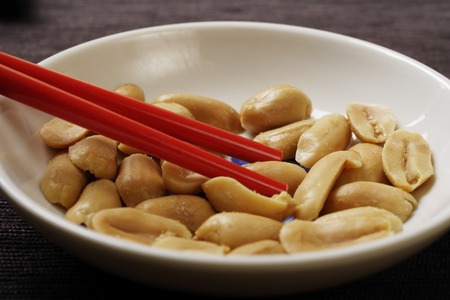 close up of red chopsticks picking up peanutsの写真素材