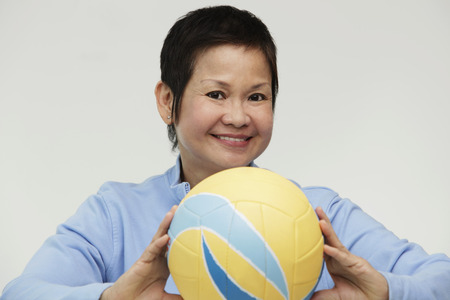 Mature woman holding a volleyball and smilingの写真素材
