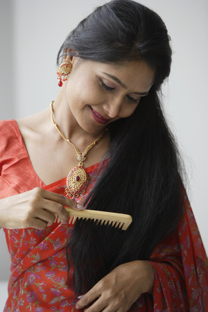 Indian woman wearing a sari and combing her hairの写真素材
