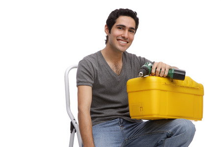 Man with toolbox and drill, sitting on ladderの写真素材