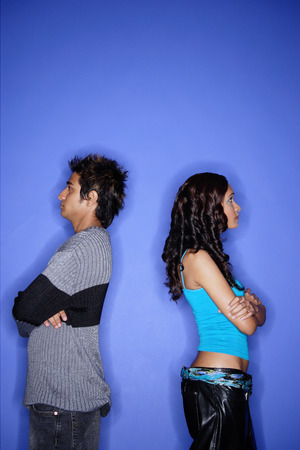 Couple standing apart against blue wallの写真素材