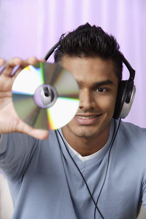 young man with headphones on, holding compact disc in front of himの写真素材