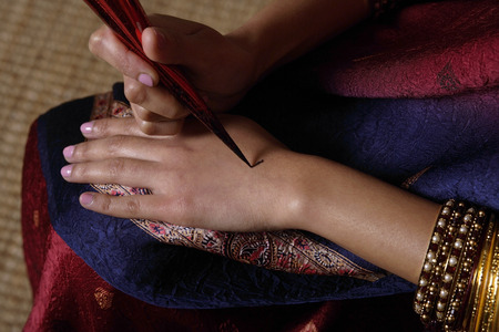 Indian woman painting hand with hennaの写真素材