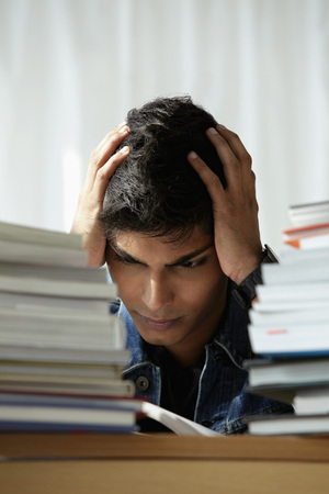 young man holding head and reading book