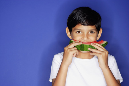Boy looking at camera, eating watermelon