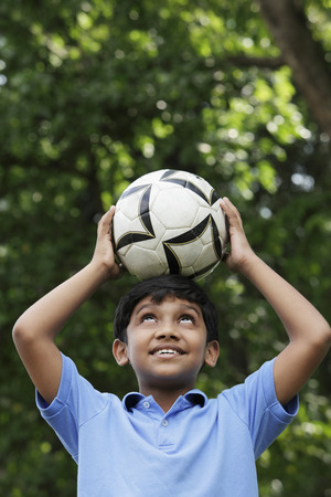 Young boy balances ball on his headの写真素材