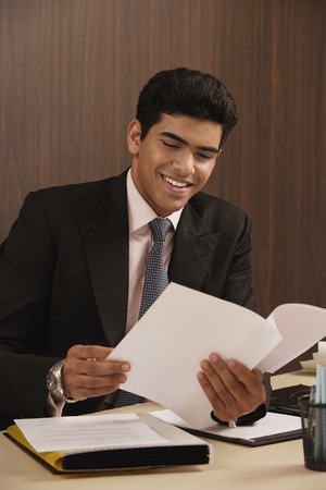Businessman reading paper and smilingの写真素材