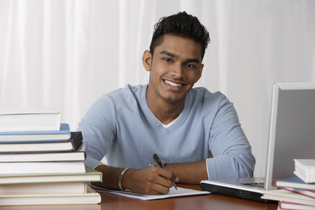 young man sitting at his desk, writingの写真素材
