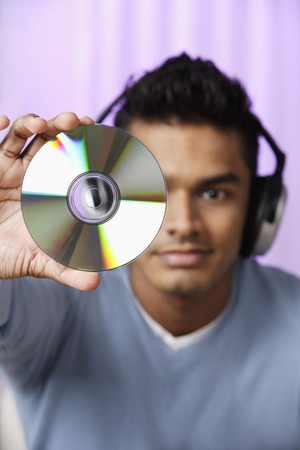 young man with headphones on, holding compact disc in front of himの写真素材