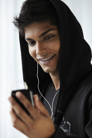 Head shot of young man wearing hooded sweat shoot and listening to musicの写真素材