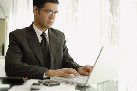 Businessman sitting at desk, using laptopの写真素材