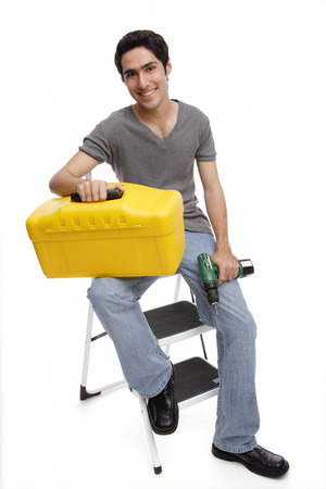 Man sitting on ladder, holding toolbox and drillの写真素材