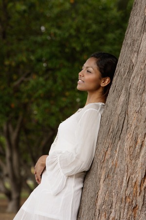 woman leaning on tree, looking awayの写真素材