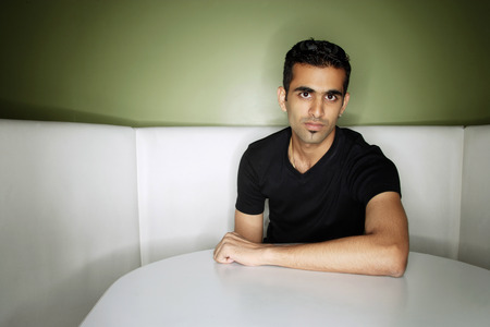 Young man sitting in booth, looking at cameraの写真素材