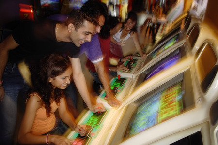 Young adults in video arcade, playing gamesの写真素材