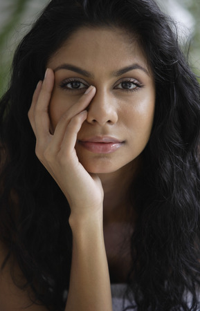 Head shot of Indian woman with hand on her face.