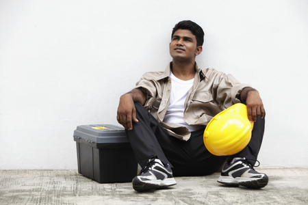 man sitting on ground holding construction hatの写真素材