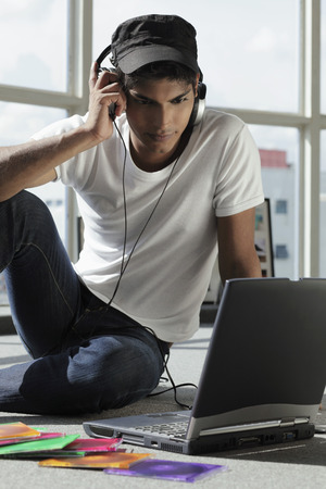 young man listening to music while looking at laptopの写真素材