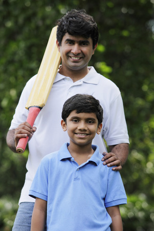 Father holding cricket bat with son