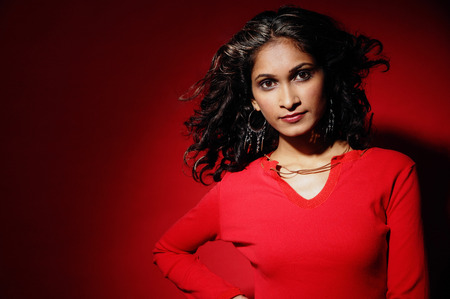 Woman looking at camera, wearing red blouse against red backgroundの写真素材
