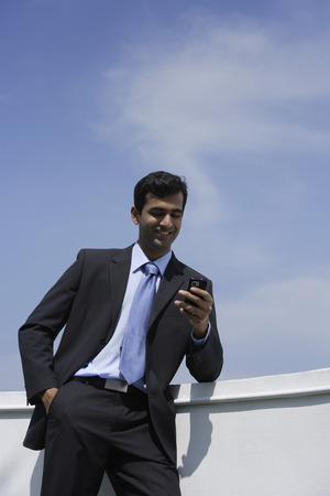 Indian businessman reading text message outside.の写真素材