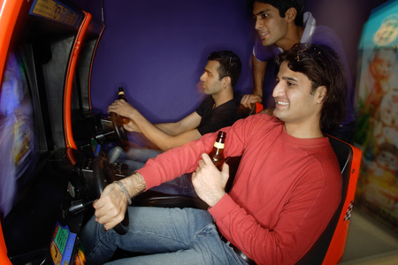 Young men in amusement arcade playing video gamesの写真素材