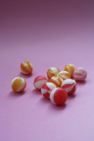 unwrapped hard candies on pink paperの写真素材